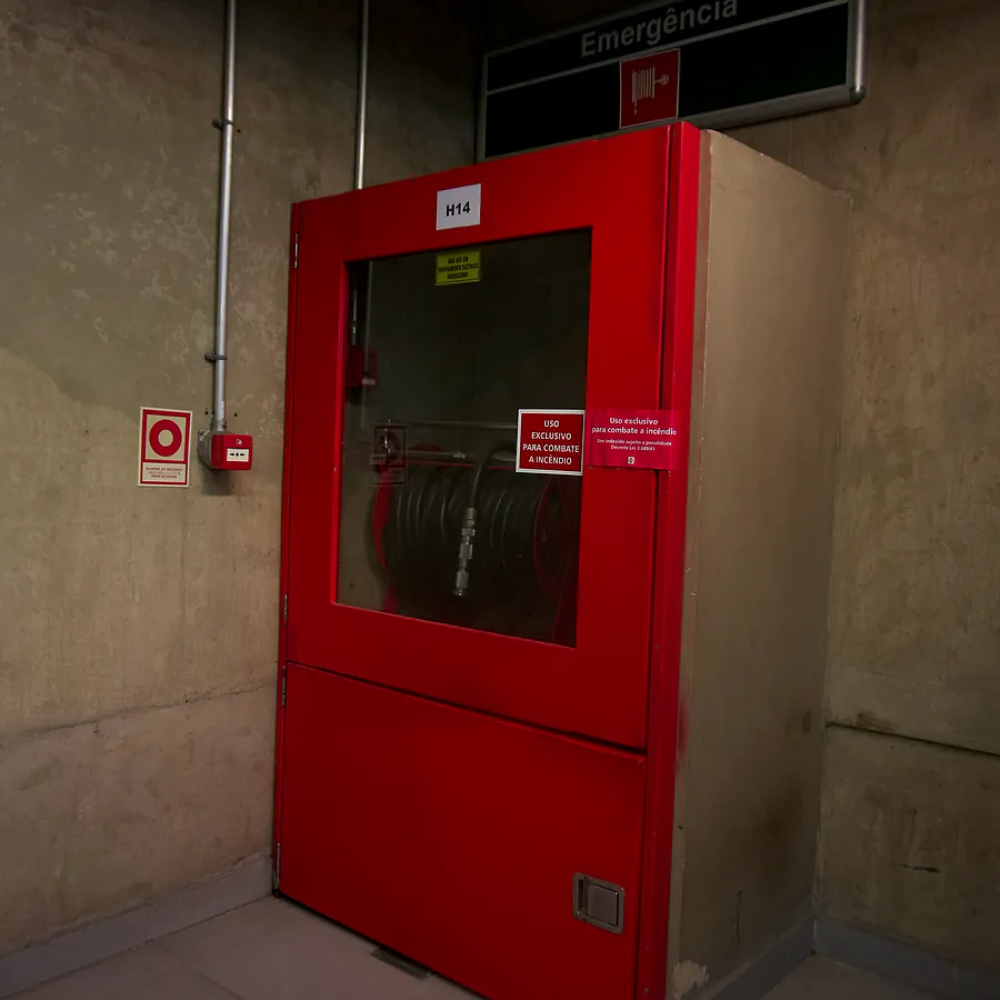 Abrigo de hidrante vermelho com sinalização em parede de concreto